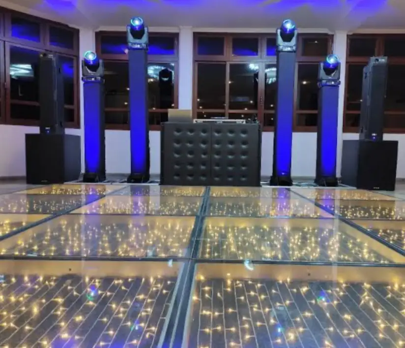 Estrutura com caixas de som, subwoofers, colunas iluminadas com moving heads, cabine de DJ e pista de LED