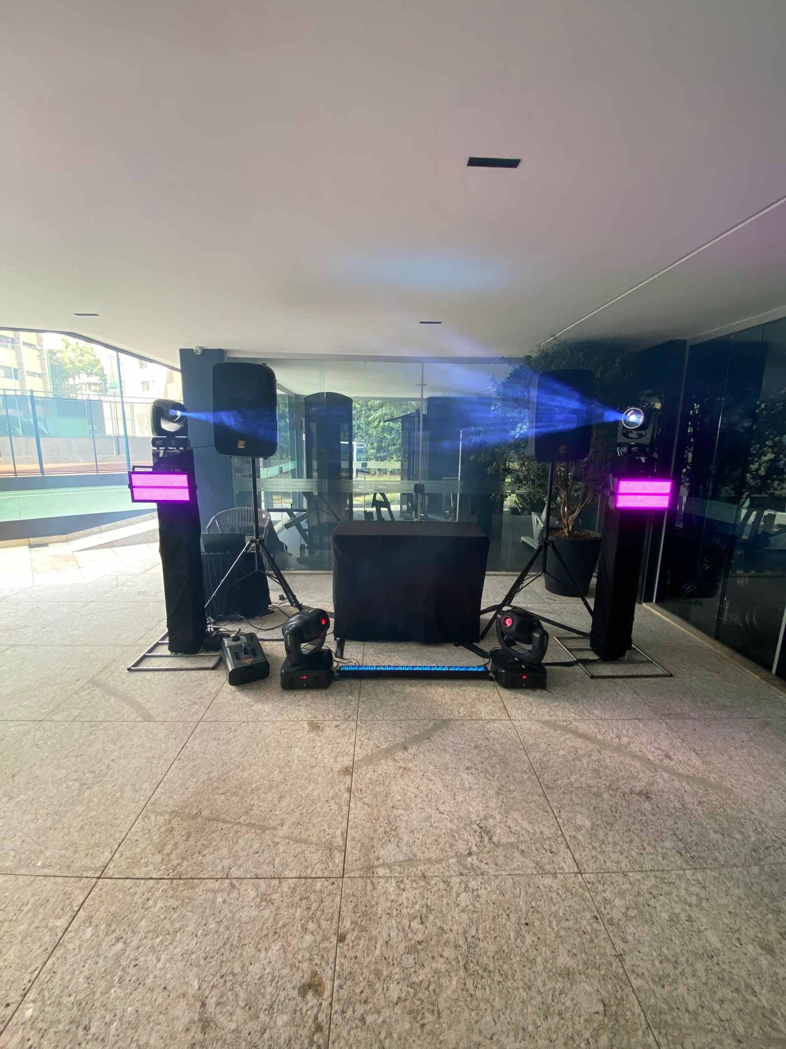 Som e iluminação montados e prontos antes da festa: caixas, colunas com luz, moving heads e cabine de DJ em salão envidraçado