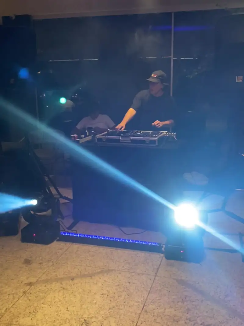 Cabine de DJ à noite com feixes de moving heads e barra de LED acesa