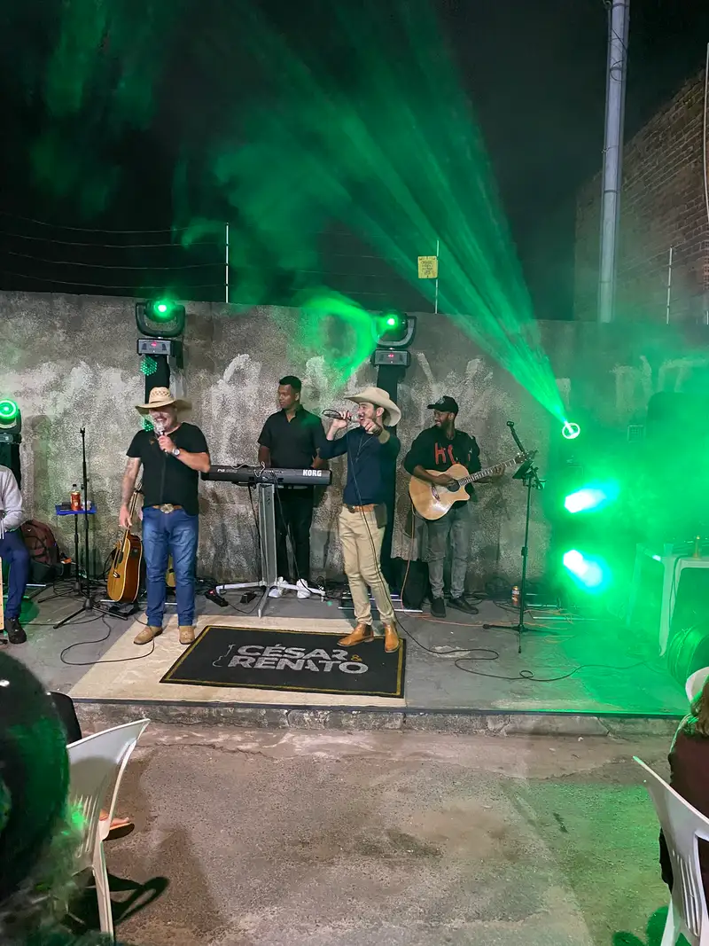 Dupla se apresentando com fachos de luz verde e moving heads ao fundo