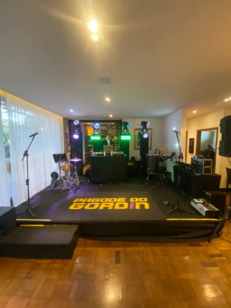 Estrutura para show ao vivo com DJ, bateria, microfones, caixas de som e moving heads montados no salão