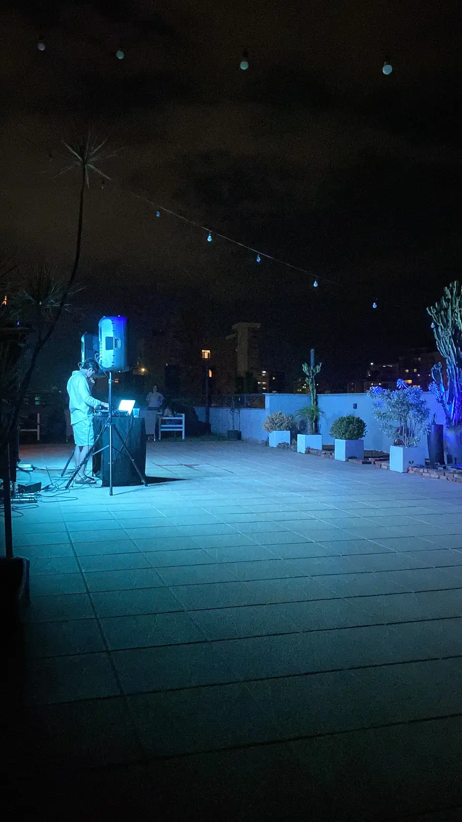 Caixas de som iluminadas em azul ao lado da cabine de DJ em uma cobertura à noite